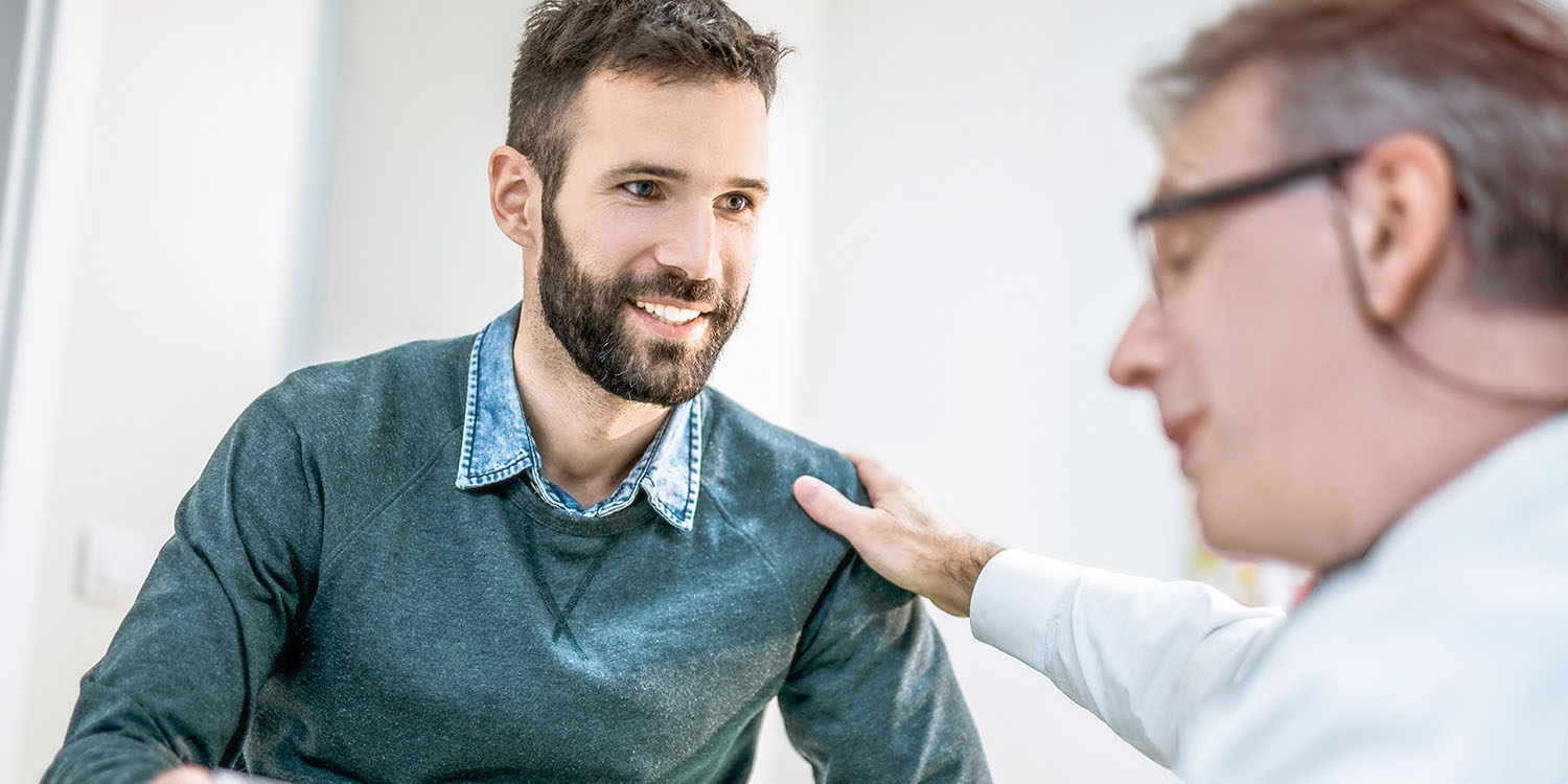 A younger prostate cancer patient consults with a radiation oncologist about proton therapy