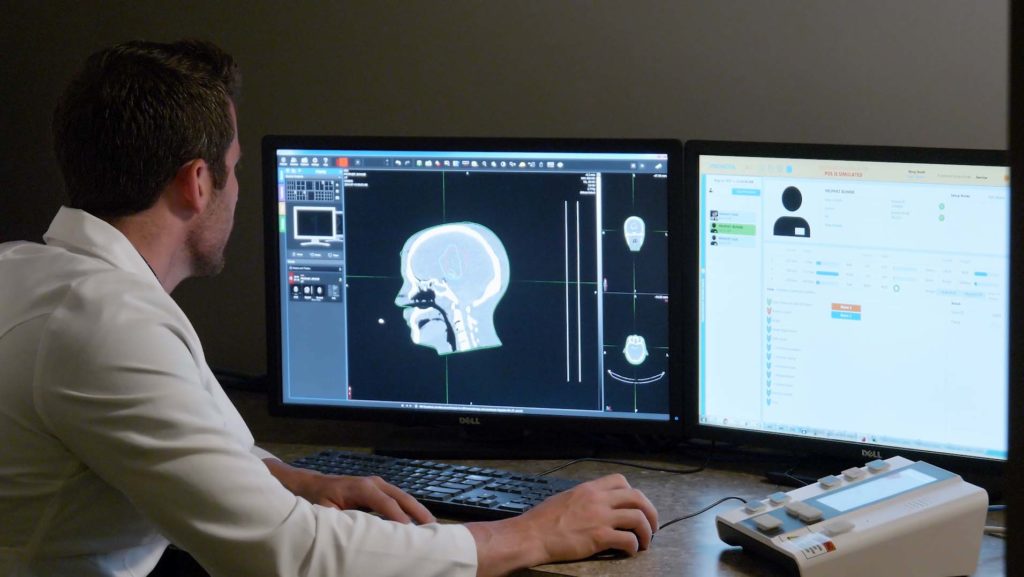 A radiation therapist reviewing a proton therapy treatment plan for head and neck cancer