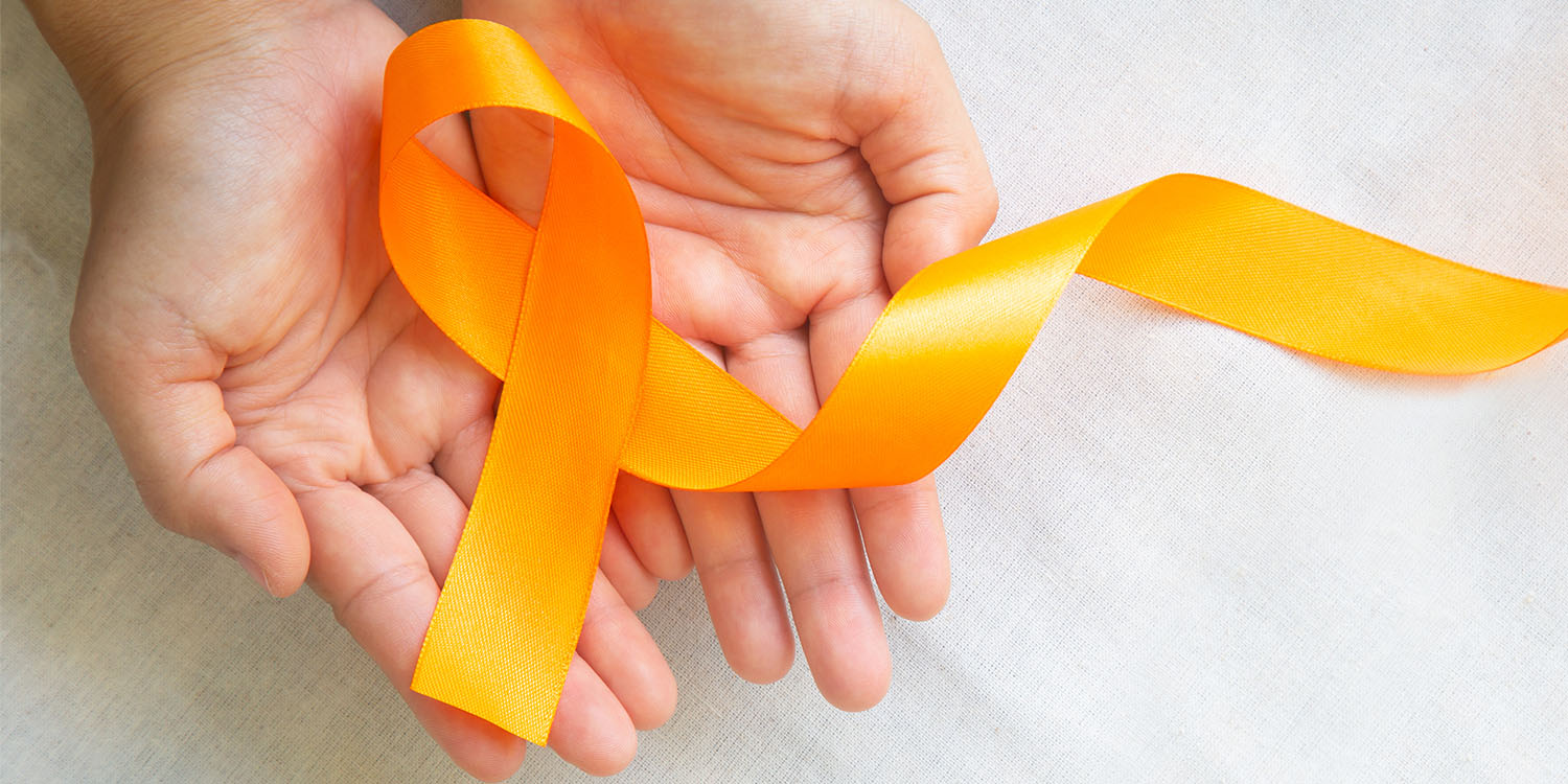 Hands holding an orange ribbon for skin cancer awareness month