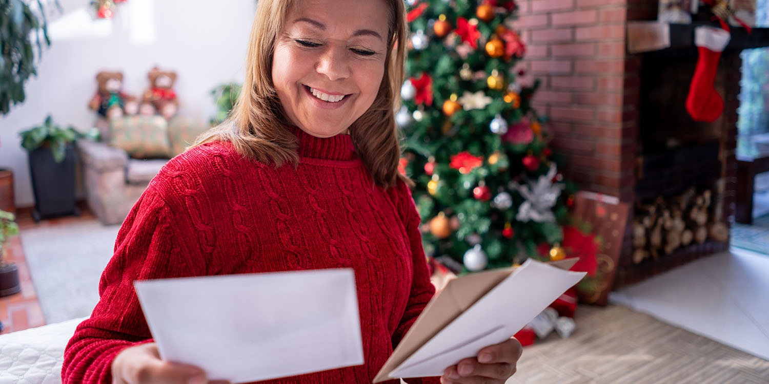 A woman smiles as she prepares a holiday card for someone with cancer