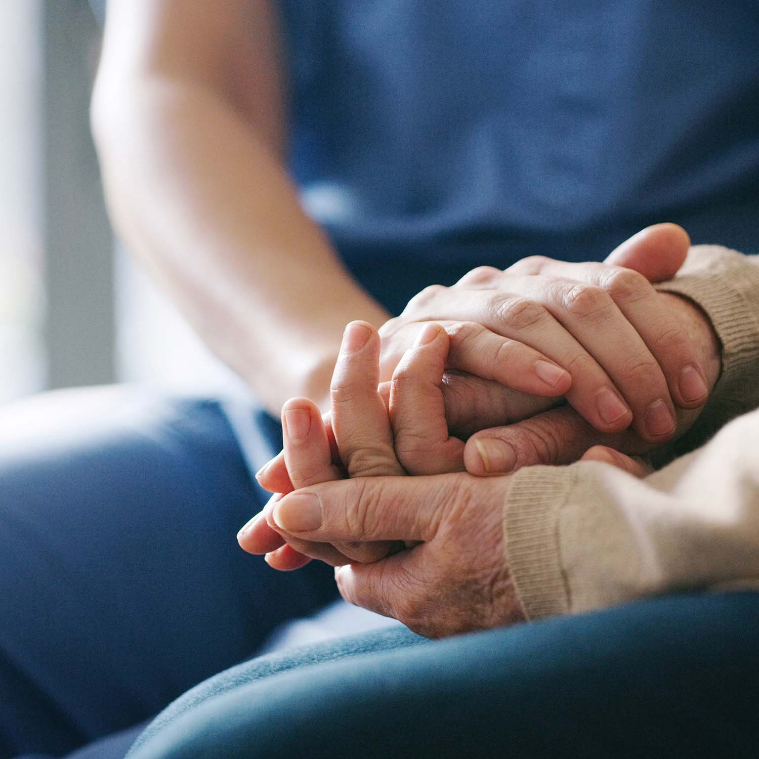 Caring healthcare worker holds hands with a patient